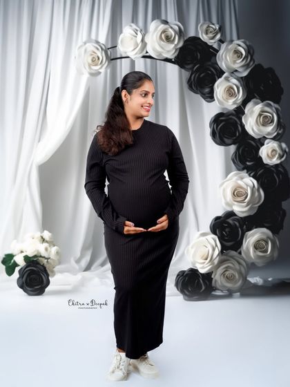 A modern and chic black-and-white theme. The simple black dress and the paper flower arch create a sophisticated and artistic look.