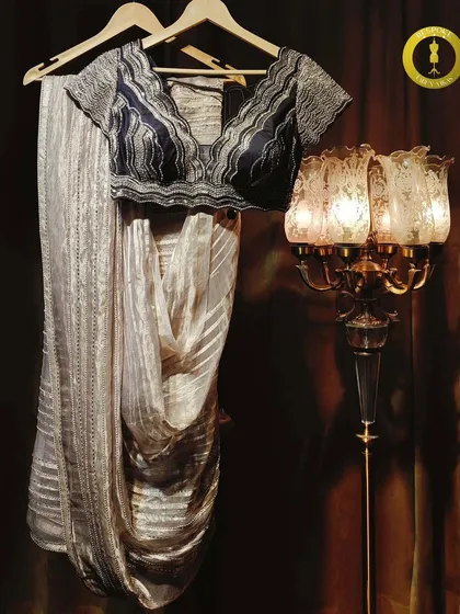 Sparkle and elegance woven together. This stone-work saree features a unique blouse with wave-like embroidery, paired with a shimmering striped drape.