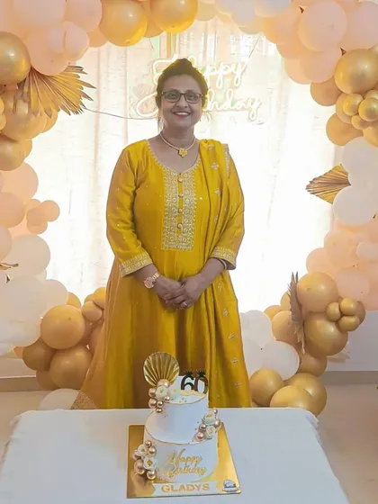 The birthday lady looking radiant as she stands by her elegant 60th birthday cake.