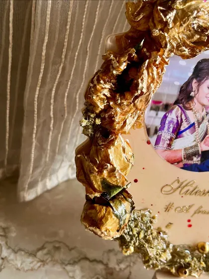 A close-up showing the 3D texture of preserved golden flowers on a custom photo frame.