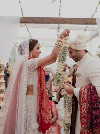The bride playfully places the garland on her groom, a fun and candid moment from the wedding ceremony we organized at Intercontinental Marine Drive.