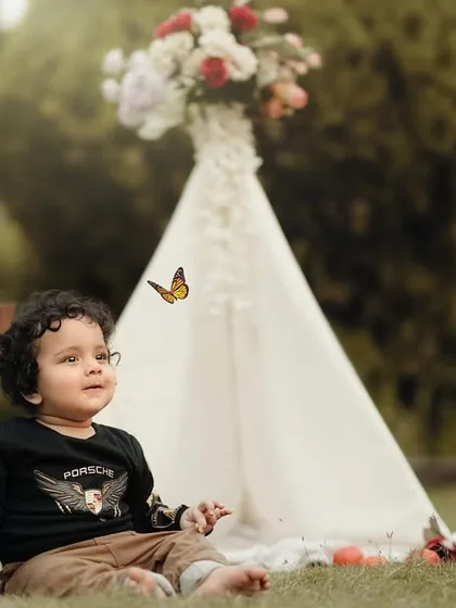 A little boy with curly hair enjoying the outdoors. The teepee and windmill in the background add to the rustic, adventurous feel of the shoot.
