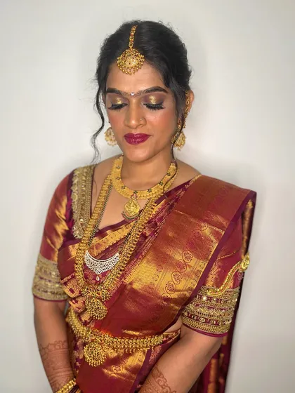 This bride's makeup features a glamorous golden shimmer on the eyes and a bold berry lip, a stunning combination for a South Indian wedding.