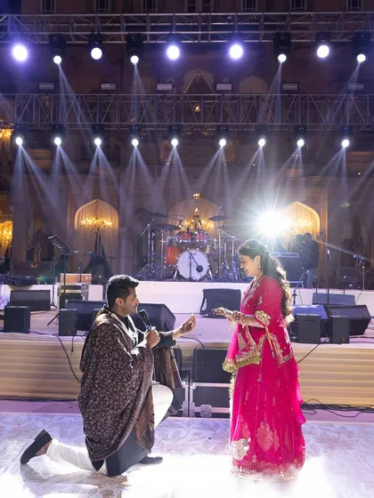The Sangeet stage, set up for a live band performance against the magnificent backdrop of the palace, lit by professional stage lights.