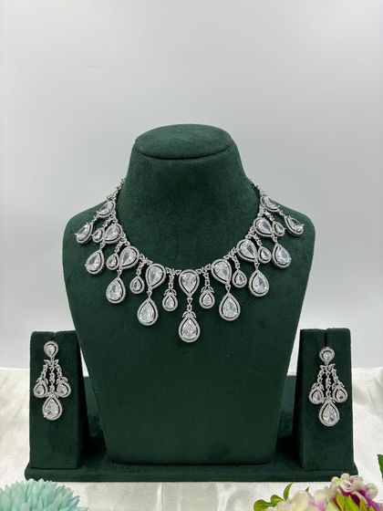 A contemporary silver-plated necklace set with teardrop-shaped stones. This design is available in emerald green, pink, red, and dark blue, offering a sleek and modern look for any occasion.