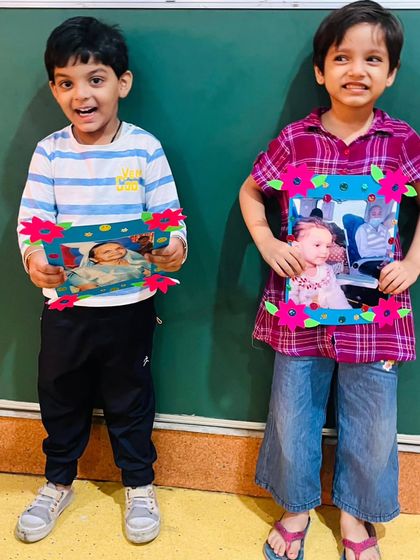Two more students display their colorful, handmade photo frames, filled with love for their grandparents.