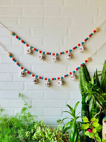 Our 'Khanak' beaded bell buntings are perfect for adding a touch of elegance to any space. This image shows two buntings in a red, blue, and white combination, ideal for doorways or temple spaces.