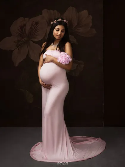 A soft, dreamy portrait in a flowing pink gown. The floral elements and gentle pose create a feeling of romance and delicate beauty.