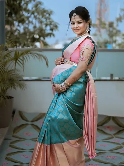 A side profile showcasing the beautiful drape of the saree and the client's baby bump. A moment of pure maternal beauty.