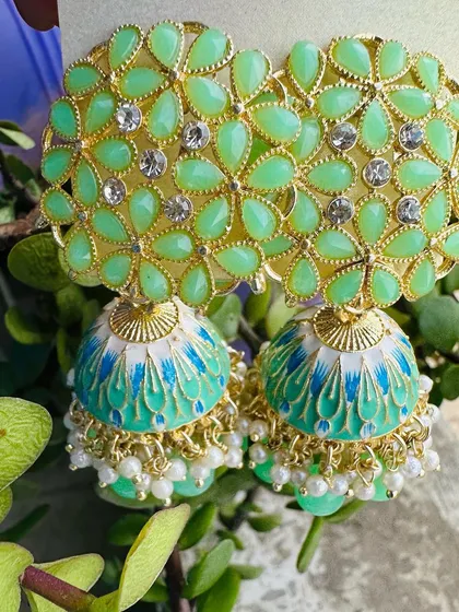A refreshing mint green pair of jhumkas. The light green floral top and hand-painted dome are perfect for daytime events and summer weddings.