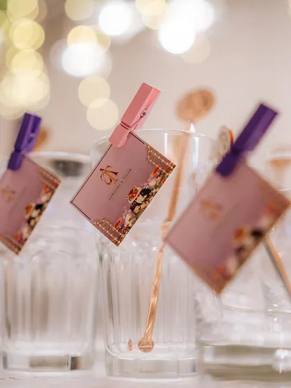 A small detail that shows personalization. Custom-printed tags with the couple's monogram are clipped to drinking glasses, adding a thoughtful and branded touch to the bar service.