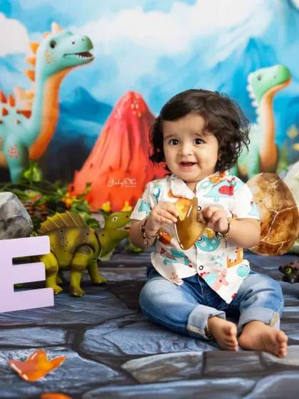 This little explorer is holding onto a dinosaur egg, full of curiosity. The 'ONE' sign adds a perfect touch to this first birthday portrait.