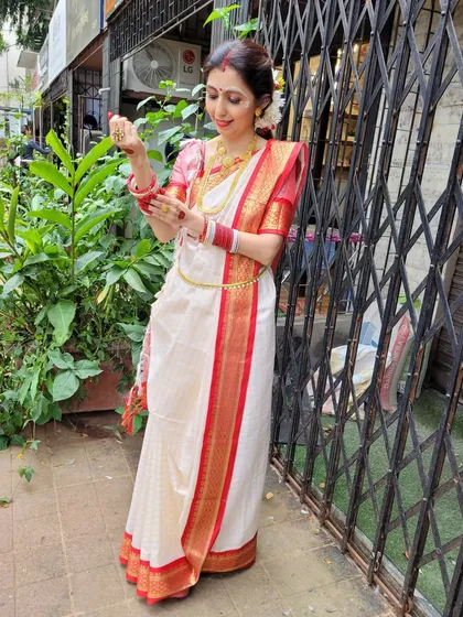 The classic white and red Bengali saree, styled with traditional gold jewelry. I emphasize how the drape can be accessorized to enhance its festive and cultural appeal.
