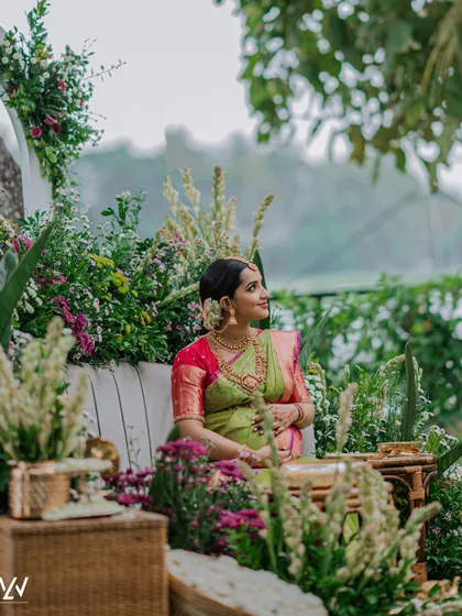 A wide shot of the beautiful Valaikappu setup. The mother-to-be looks like a goddess in her perfectly draped saree.