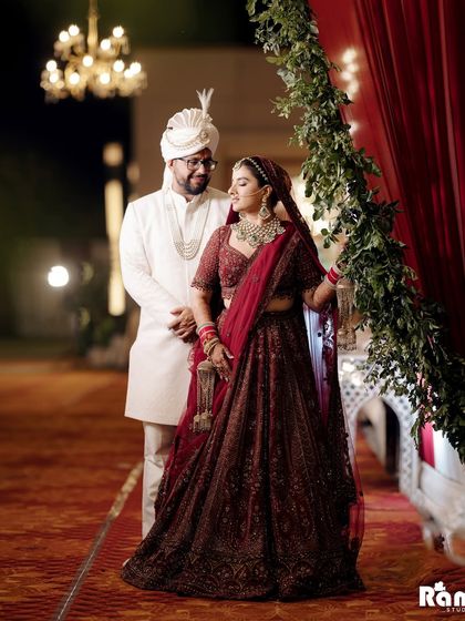 A beautiful night-time portrait of the couple standing under an archway of greenery and lights, creating a magical and romantic atmosphere.