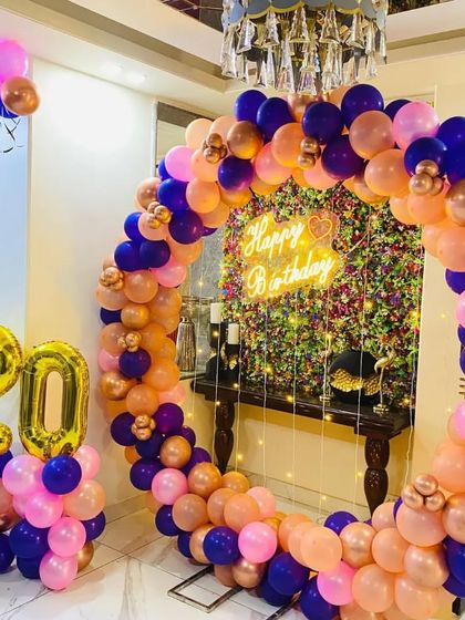 A colorful 20th birthday celebration with a balloon ring in shades of pink, peach, and blue, with large gold foil numbers.