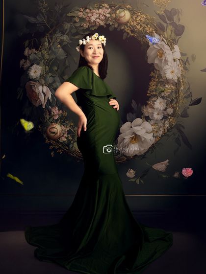A joyful portrait with a mom-to-be wearing a floral crown against a large floral wreath, creating a bohemian and natural feel.