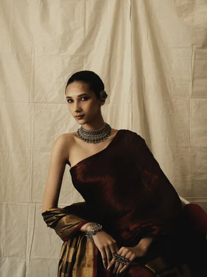 This portrait showcases an off-shoulder draping of the saree, a modern twist on a classic garment. The lighting is soft and painterly, creating a moody and artistic feel.