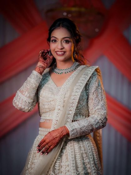 A stunning portrait of the bride, Kasturi, in her elegant white lehenga for her engagement ceremony. Her smile and the intricate details of her outfit are beautifully captured.