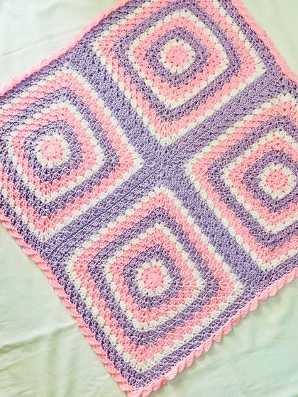 An angled view of the four-square granny blanket, highlighting the symmetry of the design. This is a timeless pattern that makes a perfect baby shower gift.