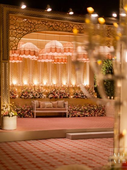 The stage at the 'Sitara Mahal' event, featuring a backdrop of illuminated panels and whimsical umbrella-like chandeliers. The space was designed for a couple who loves timeless elegance.