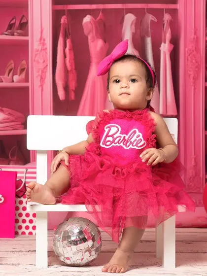An 11-month-old baby girl enjoys her moment in the spotlight during a Barbie-themed milestone session. The set includes a custom Barbie box and accessories.