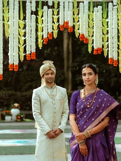 The couple stands under a stunning entrance arch made of coconut leaf toran, white chrysanthemums, and marigolds. This type of traditional South Indian floral work is perfect for auspicious beginnings.