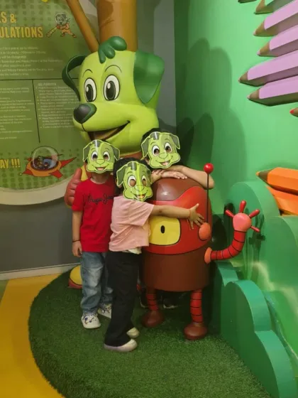 Masked up for fun! Three kids wearing Tinga masks hug our mascot Popsy, showing their love for the characters.