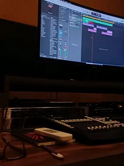 A close-up of my workstation during a writing session. You can see the audio tracks on the screen, my notebook for lyrics, and my glasses for the long hours.