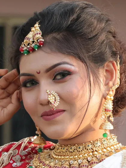A detailed shot focusing on the bride's expressive eyes and traditional nath. The makeup is expertly applied to enhance her natural beauty.