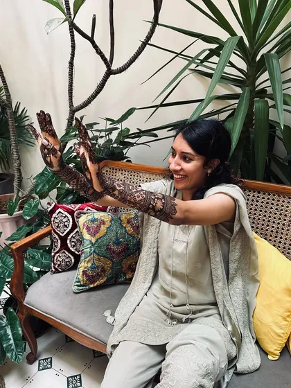A happy, candid shot of a client showing off her intricate lotus-themed mehndi design.