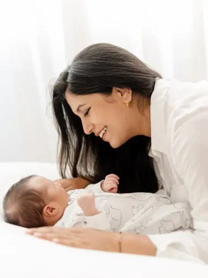 A new mother smiling as she lies next to her newborn baby. This simple, clean setup focuses entirely on their sweet interaction.