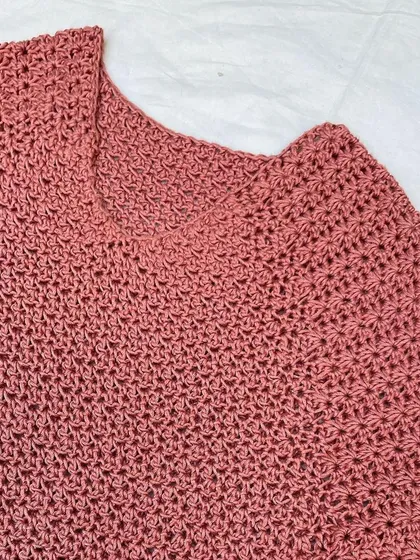 A detail shot of the neckline and shoulder construction of the Etoile Sweater. The stitch pattern is consistent and creates a lightweight, breathable fabric for this crochet pullover.