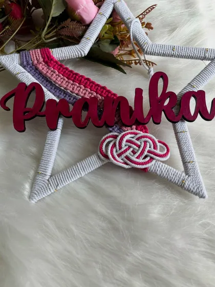 A close-up of the 'Pranika' star-shaped hanging, showing the texture of the wrapped frame and the custom name.