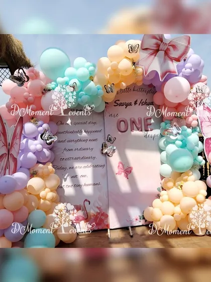 A full view of the butterfly-themed backdrop for the twins' birthday. The setup includes large pink butterfly wings and a soft, pastel color palette.