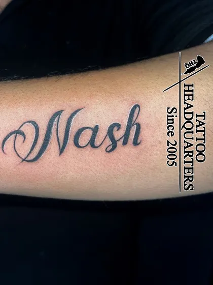 The name "Nash" in a clean, elegant cursive script, a classic and timeless name tattoo.