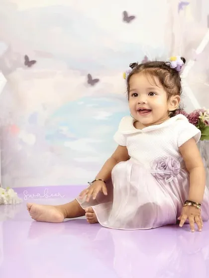 A bright, happy smile from this one-year-old, surrounded by a dreamy, pastel-colored butterfly theme in the studio.