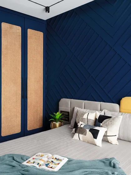 A view of the custom wardrobe with rattan paneling, which adds a touch of natural texture and complements the deep blue accent wall. The design is both contemporary and timeless.