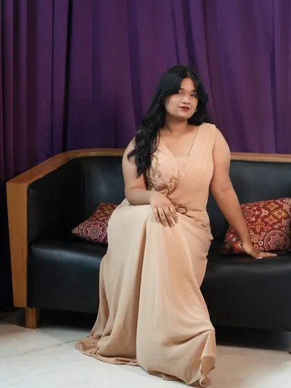 You don't need a big budget to look amazing. This elegant beige gown is part of my affordable rental range, sitting perfectly on our black leather sofa prop against a deep purple backdrop. It's a great setup for portraits or content creation.
