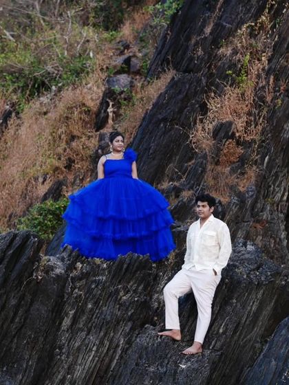 A dramatic pre-wedding shoot on a rocky landscape. The royal blue ball gown provides a stunning contrast against the natural, rugged terrain.