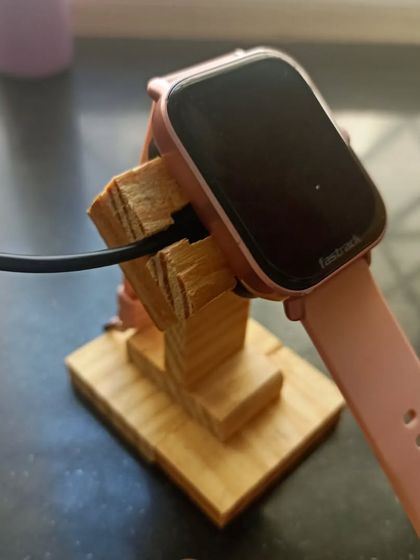 The smartwatch charging stand in use. The design holds the watch securely at an angle, making it easy to see the screen while it charges.
