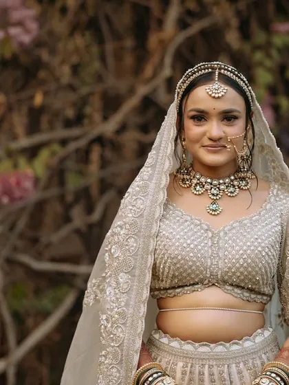 A stunning portrait of the bride in her elegant white and gold lehenga, looking serene and beautiful.