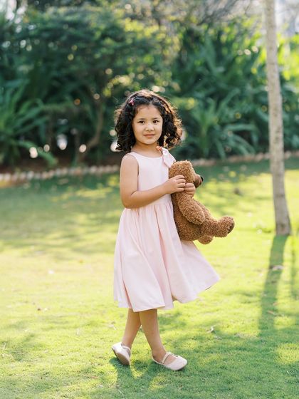 A little girl in a pink dress, holding her teddy bear. The soft, natural light makes this portrait feel so gentle and sweet.