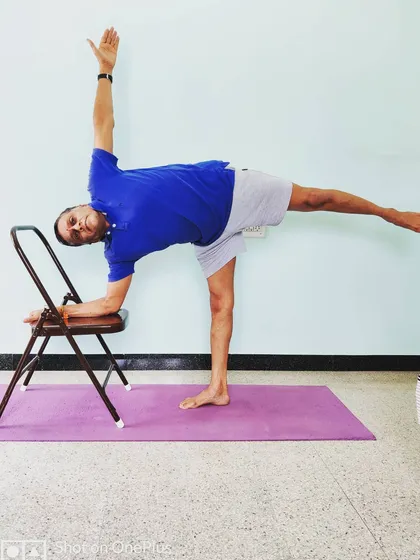 Ardha Chandrasana (Half Moon Pose) with the forearm resting on a chair. The support allows you to focus on stacking the hips, opening the chest, and finding balance.