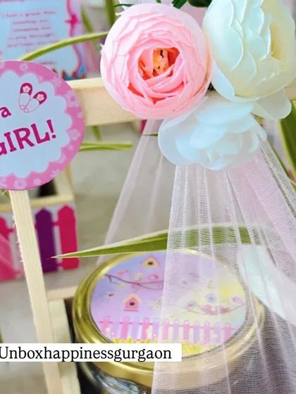 A close-up of the "It's a Girl!" tag and the delicate floral arrangement on a plant-based return favor.