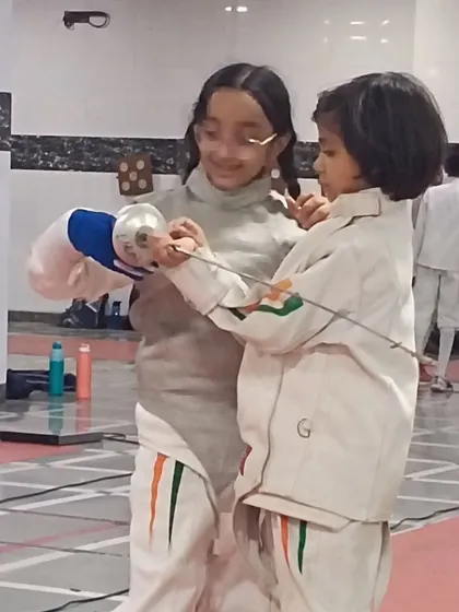 Our club is a family where experience is passed down. Here, a senior fencer mentors one of our youngest members, teaching not just technique but the values of sportsmanship and support.
