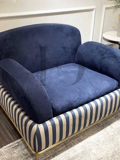 A striking armchair with a blue velvet seat and a bold, striped base with a gold-finished frame. This chair is designed for those who aren't afraid to make a statement.