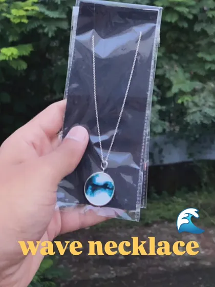 A single wave necklace, showing the round pendant and silver chain.