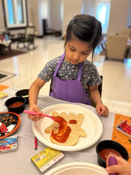 The perfect pizza starts with the perfect sauce. I show the kids how to spread the tomato sauce evenly on their ghost-shaped pizza dough before adding cheese and toppings.