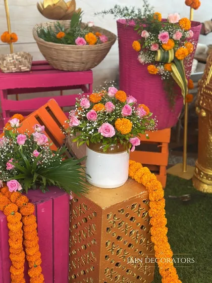 A close-up of the floral arrangements, mixing pink roses with orange marigolds. This combination of classic and traditional flowers creates a fresh and vibrant look for any pre-wedding event.